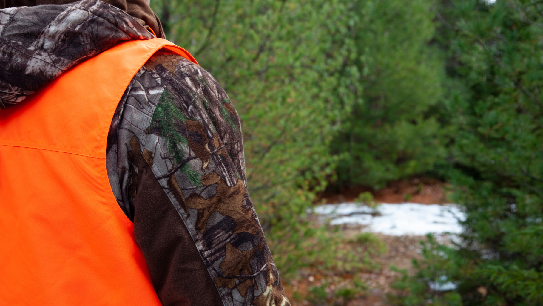 A person on the trail dressed in camo and hunter blaze orange.