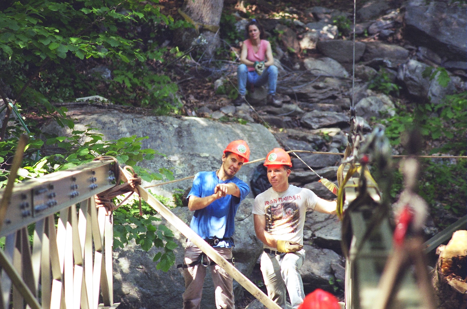 Trail builders using a rigging system to install a bridge