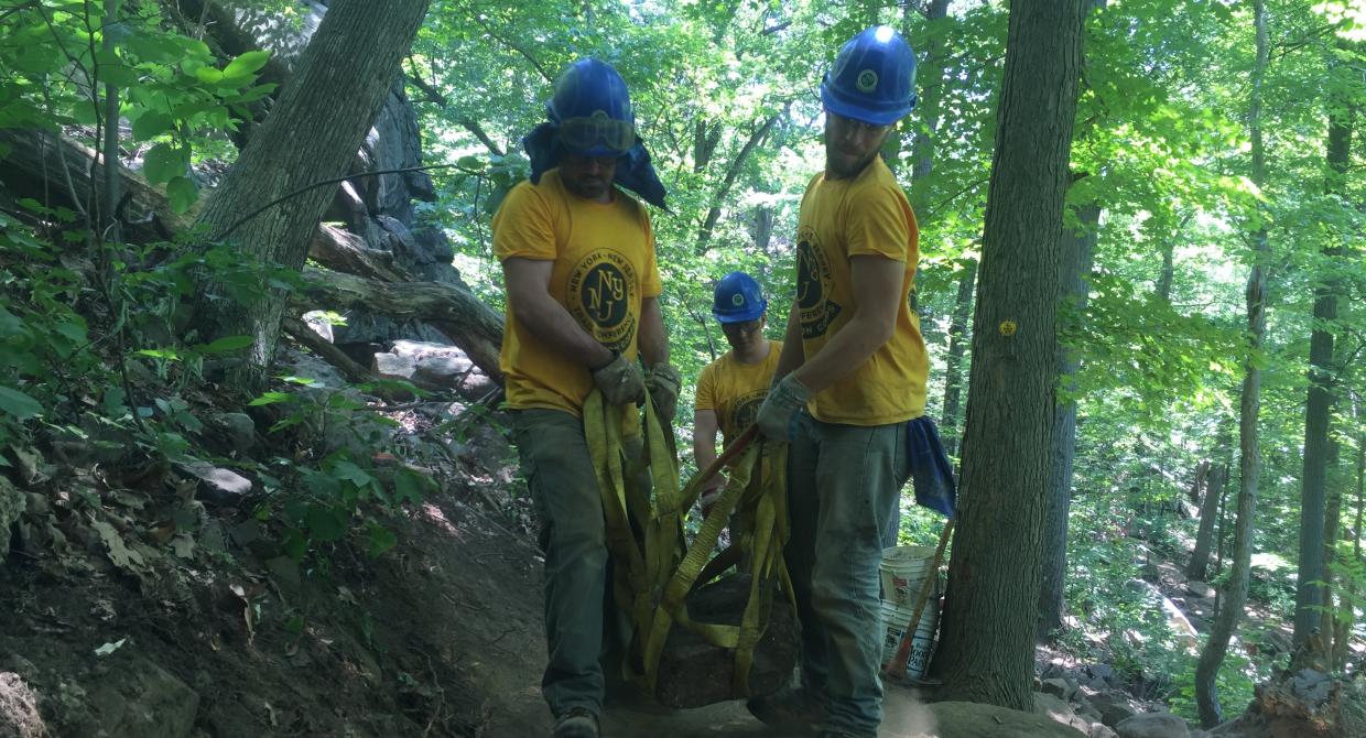 Trail crew members moving a rock.