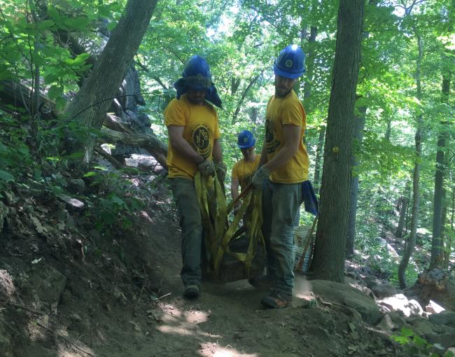 Trail crew members moving a rock.