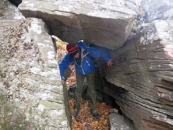 Hiker going through the tunnel under the overhanging rock on the Devil's Path on the way down Sugarloaf Mt. Photo by Daniel Chazin. 