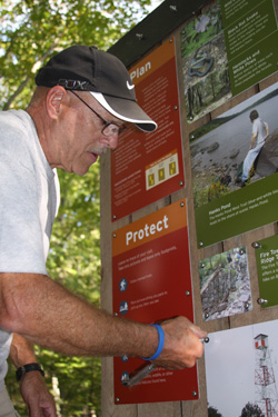 Volunteer Bob Lacorte puts final touches on new trail signs. Photo by Lou Leonardis.